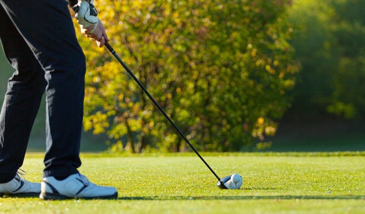 Close-up of man playing golf on green golf course. Hitting golf